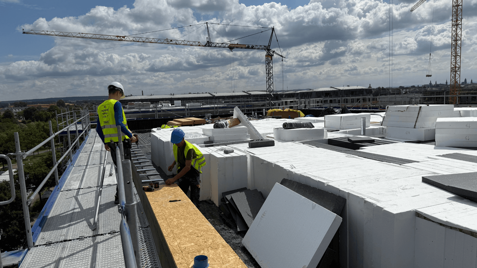 Pracownicy ROOF w kamizelkach bezpieczeństwa podczas pracy na dachu